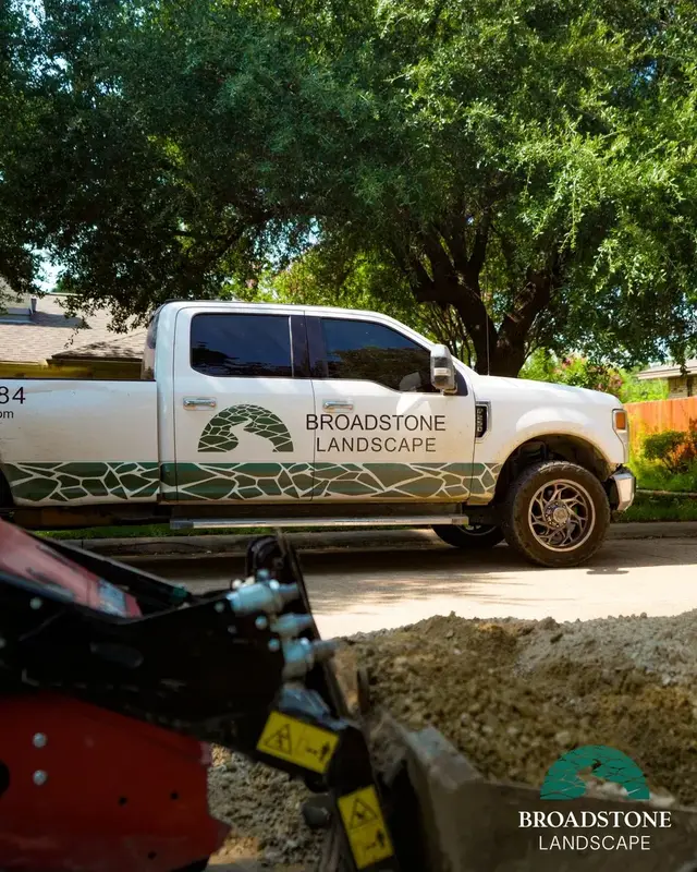 A Broadstone Landscape truck behind a loaded skid steer.
