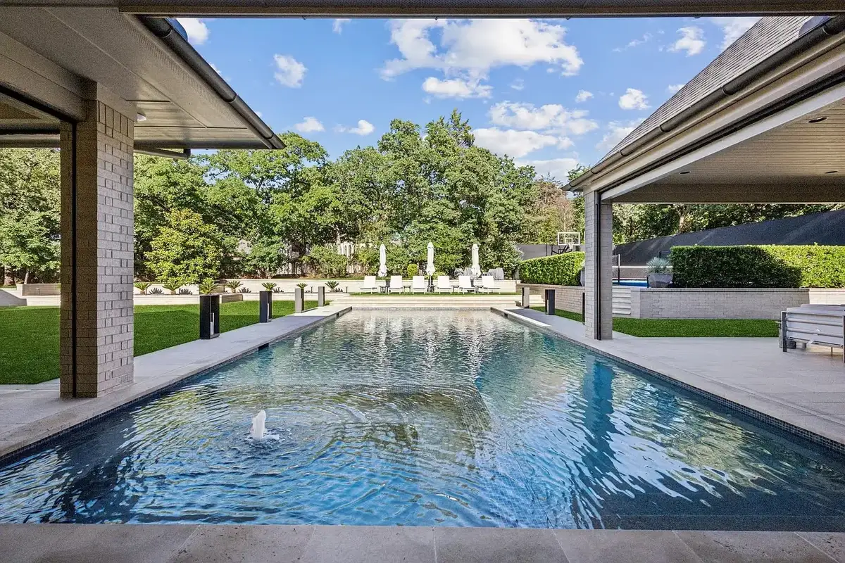 A long pool with fountains between two covered stone loggias.